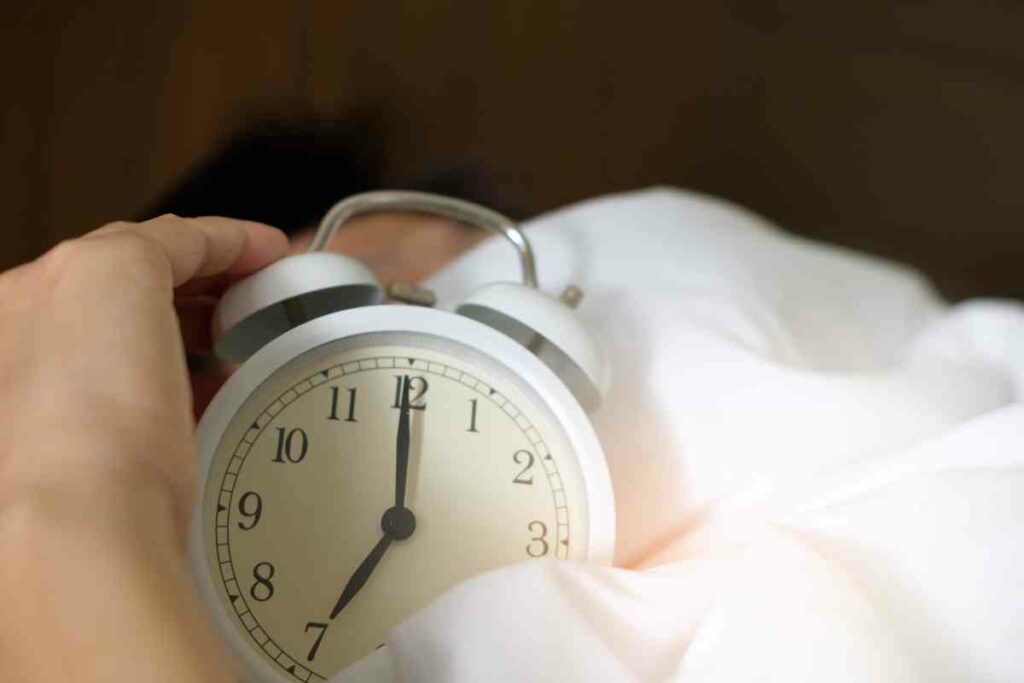 emotional resilience and sleep - alarm clock amongst bedsheets