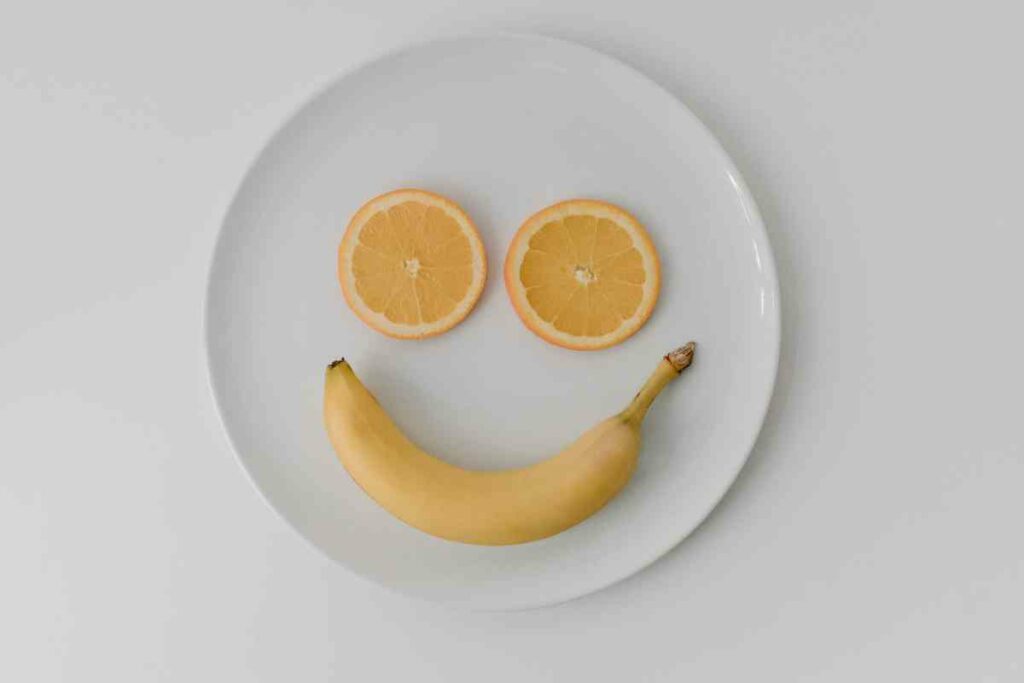 Food and mood: two orange slices and a banana make a smiley face on a plate :)