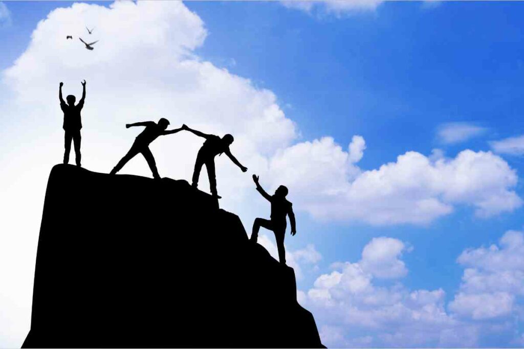 social relationships and emotional resilience - people helping each other climb a rock
